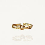 Bague fine ouverte en acier inoxydable doré avec motif nœud central et anneau effet torsadé sur fond blanc.