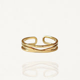 Bague fine ouverte effet double rang en acier inoxydable doré avec un anneau droit et un anneau ondulé sur fond blanc.