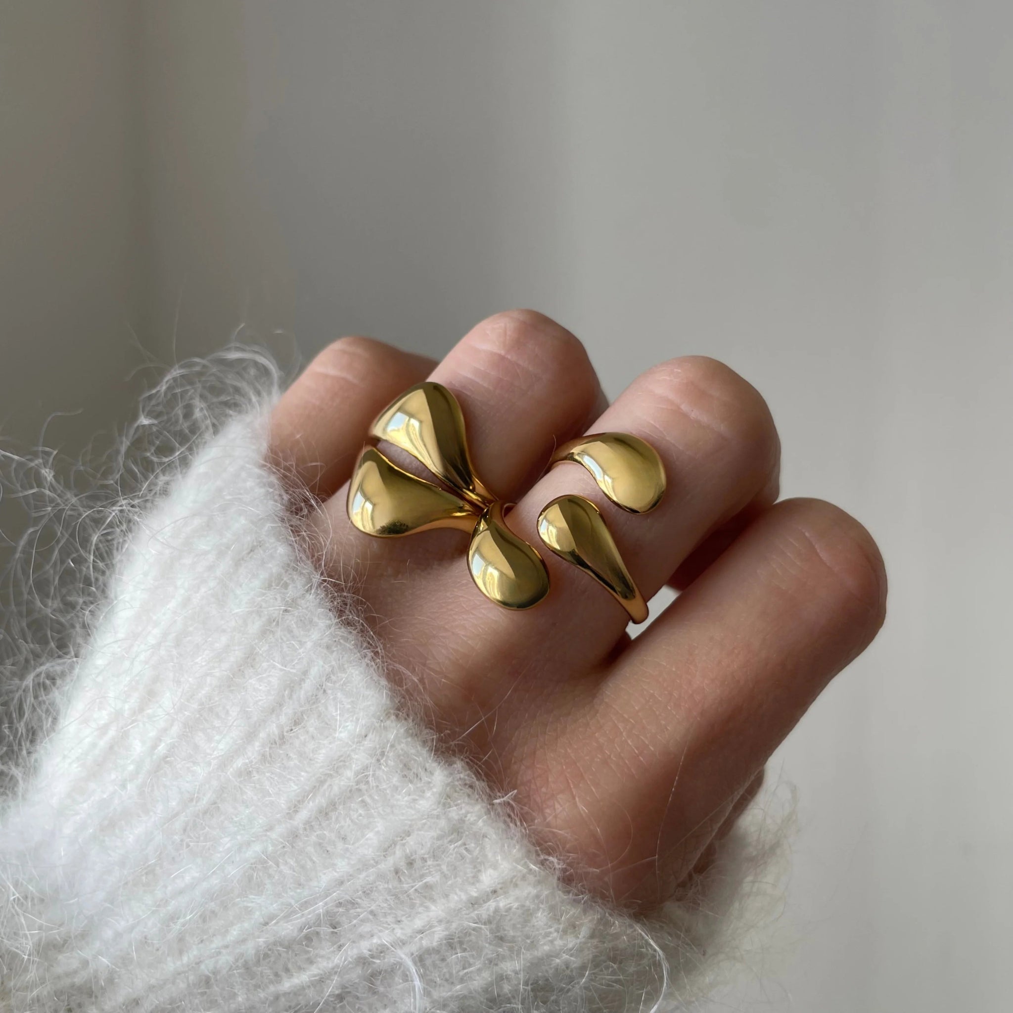 Bague graphique Alexandra portée en accumulation (stacking) avec d'autres bagues dorées fluides pour un look 'métal liquide' tendance.