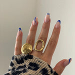 Bague géométrique Alina portée en accumulation avec une bague dôme dorée pour un look audacieux.