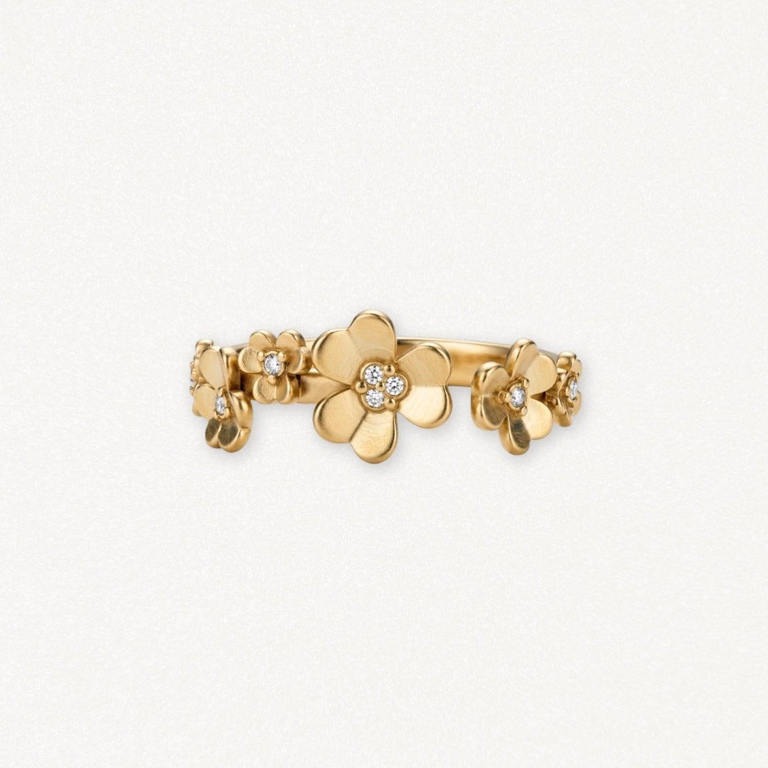 Bague en acier inoxydable doré mat, design floral avec fleurs de différentes tailles, certaines serties de brillants.
