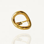 Bague large géométrique forme cercle organique et évidé en acier inoxydable doré sur fond blanc.