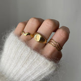 Bague vague Andrea portée en accumulation (stacking) avec une chevalière dôme lisse dorée.