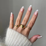 Bague vague Andrea portée en accumulation (stacking) avec une chevalière dôme lisse dorée.