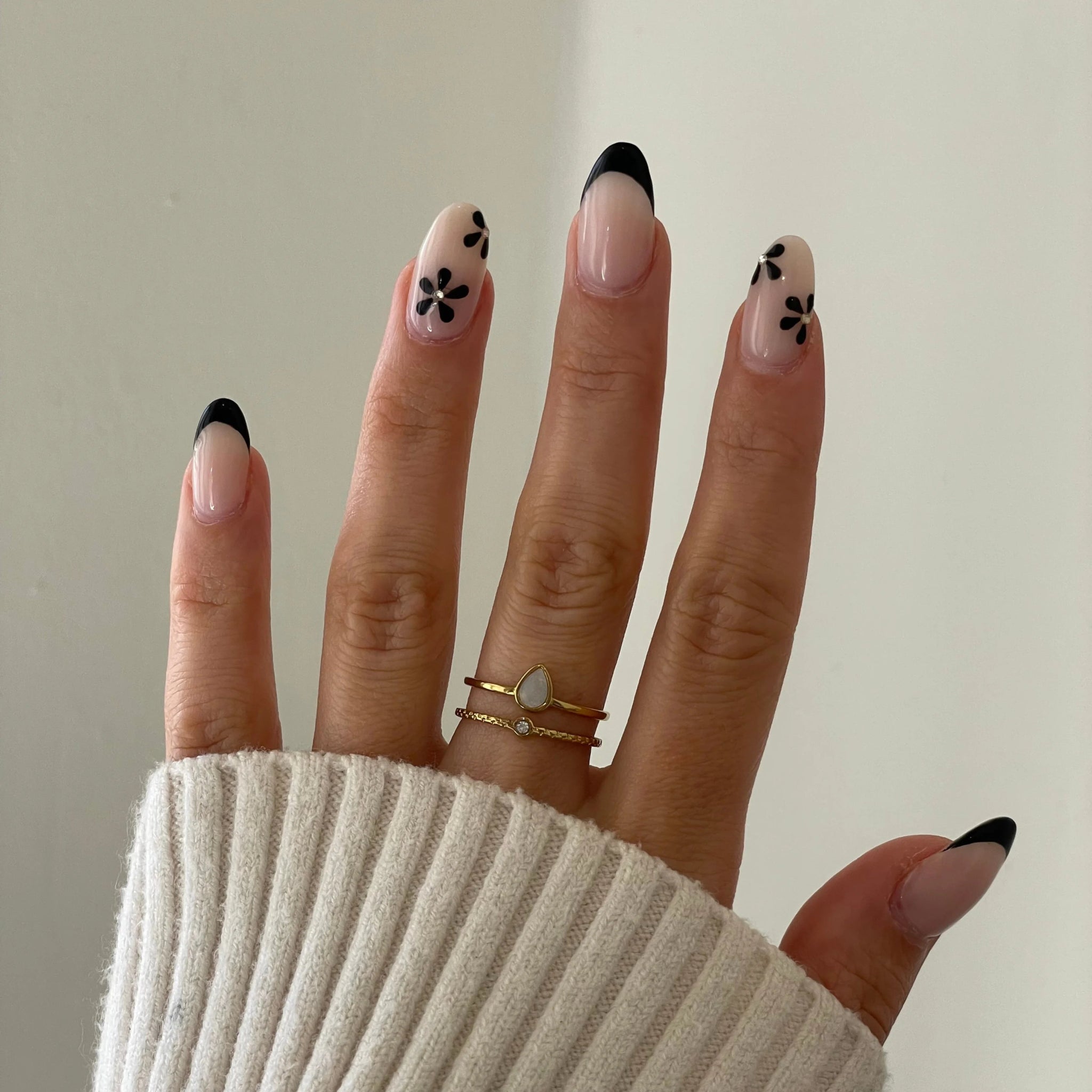 Bague fine double rang Anna portée en accumulation avec d'autres bagues dorées sur une main manucurée.