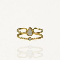 Bague ouverte effet double rang en acier inoxydable doré avec pierre blanche forme goutte et petit cristal.