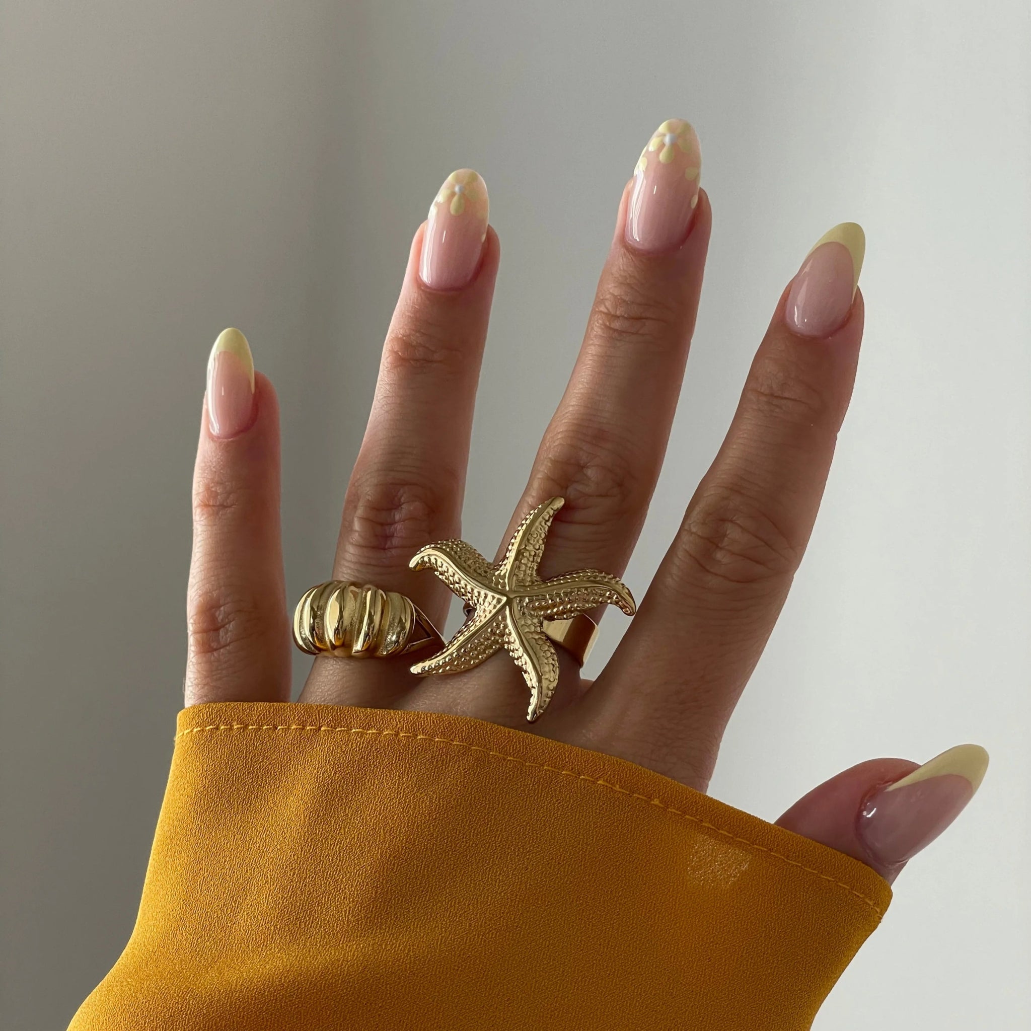 Bague Aurora portée en accumulation (stacking) avec une bague statement étoile de mer dorée.
