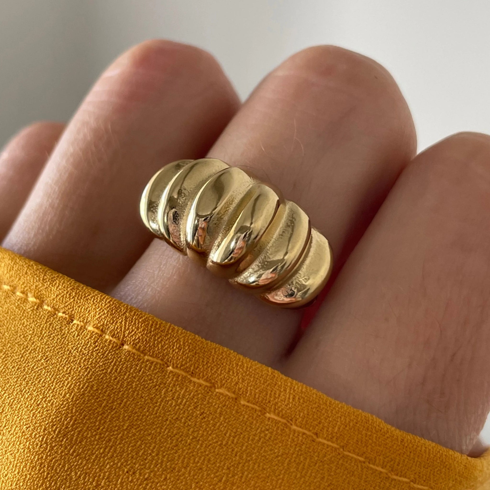 Gros plan bague Aurora forme bombée et striée portée au doigt, style vintage chic.