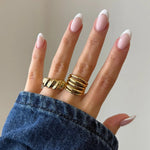 Bague croissant Berenice portée en accumulation (stacking) avec une bague multi-rangs dorée.