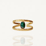 Bague ouverte double rang effet torsadé en acier inoxydable doré avec pierre ovale verte sur fond blanc.