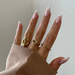 Bague Catalina portée en stacking (accumulation) avec d'autres bagues fines dorées sur une main manucurée.