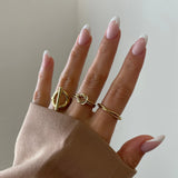 Bague Catalina portée en stacking (accumulation) avec d'autres bagues fines dorées sur une main manucurée.