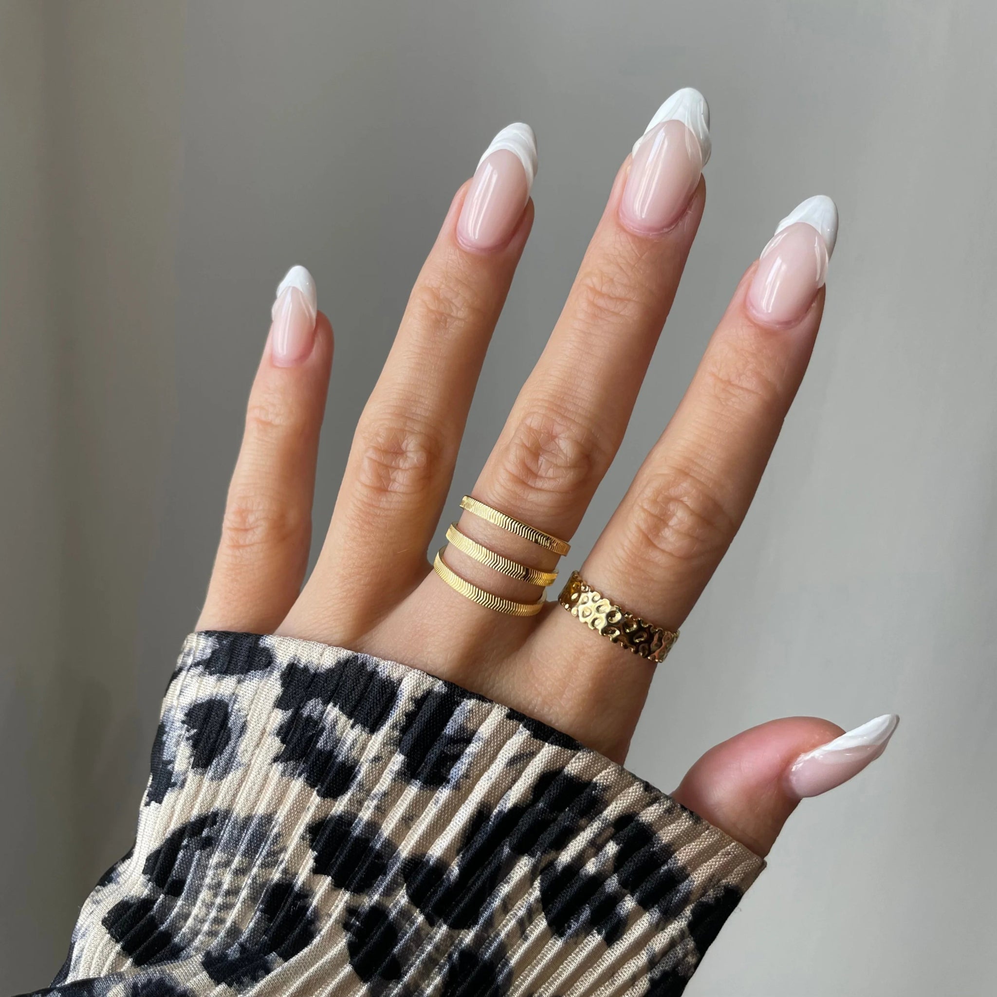 Bague bandeau Ceyda portée en accumulation (stacking) avec d'autres bagues fines pour un jeu de textures dorées.