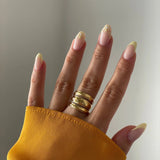 Bague multi-rangs dorée portée sur une main avec manucure, style chic et intemporel.