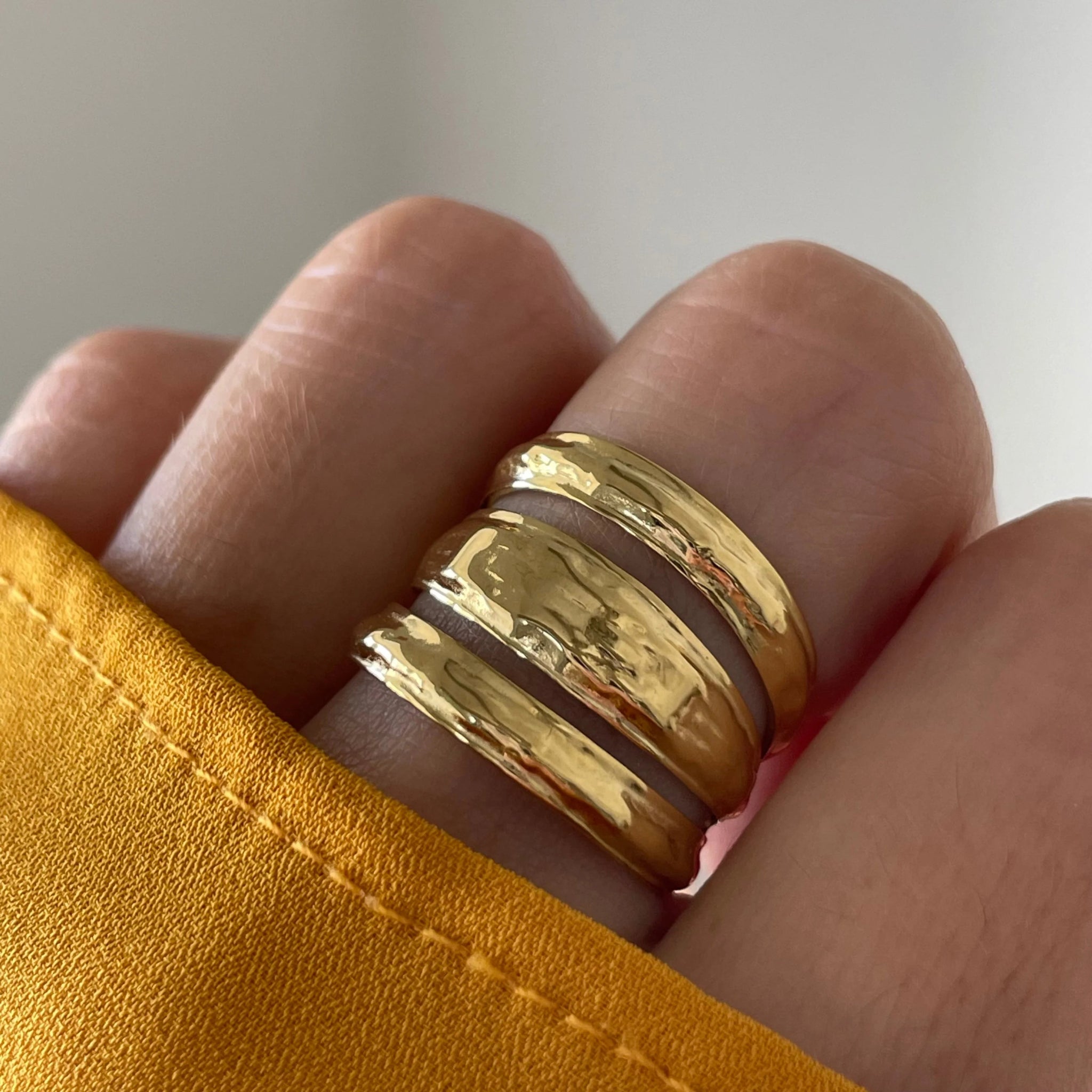 Gros plan bague Ella à trois anneaux soudés style accumulation portée au doigt.