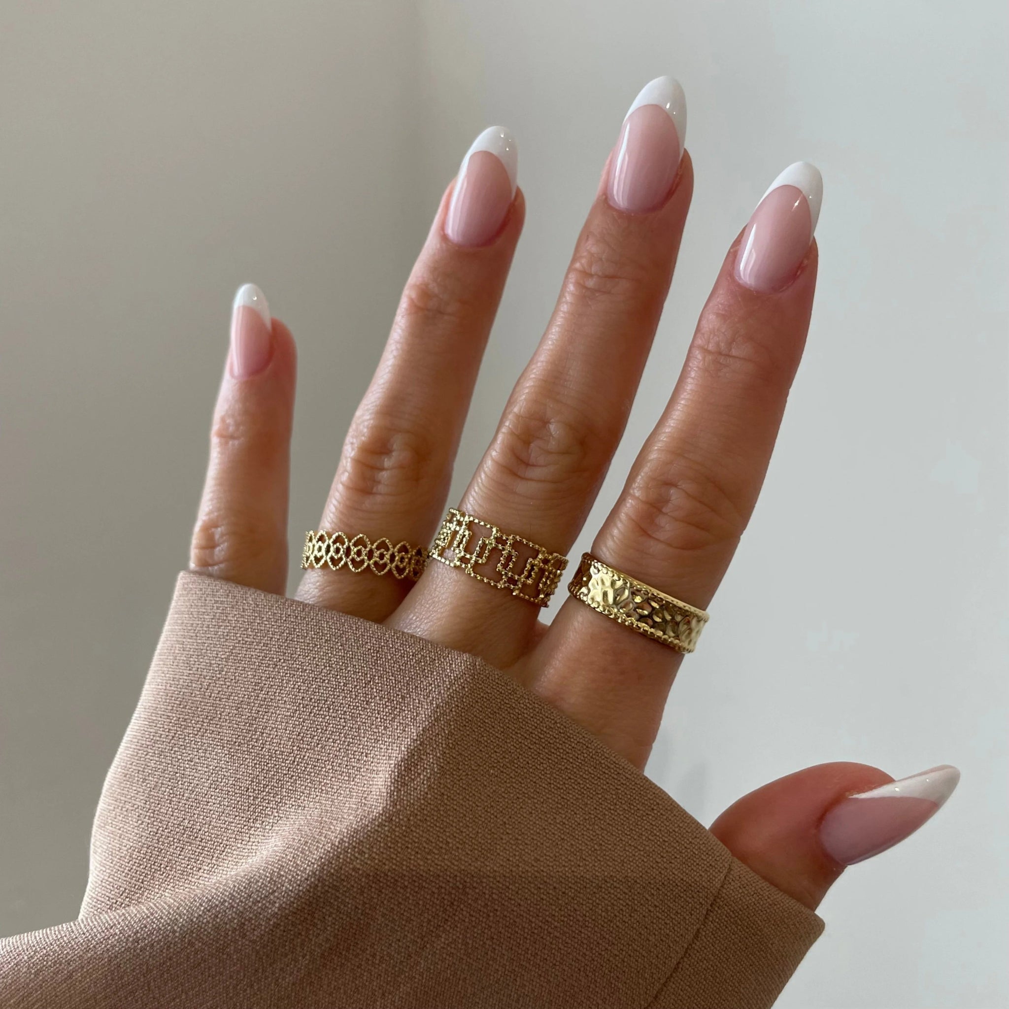 Bague bandeau Enora portée en accumulation (stacking) avec d'autres bagues fines dorées sur une main.