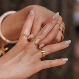 Plusieurs bagues en acier inoxydable doré, dont une bague coquillage et une bague zig-zag.