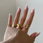 Bague Esmeralda portée en accumulation (stacking) avec d'autres bagues dorées tendance sur la main.