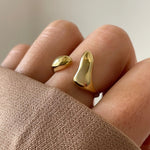 Bague dorée sculpturale portée au doigt, style moderne et abstrait, taille réglable.