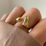 Bague dorée sculpturale portée au doigt, style moderne et abstrait, taille réglable.