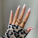 Bague double rangs Filipa portée en accumulation avec une bague cercle géométrique sur main manucurée avec pull léopard.