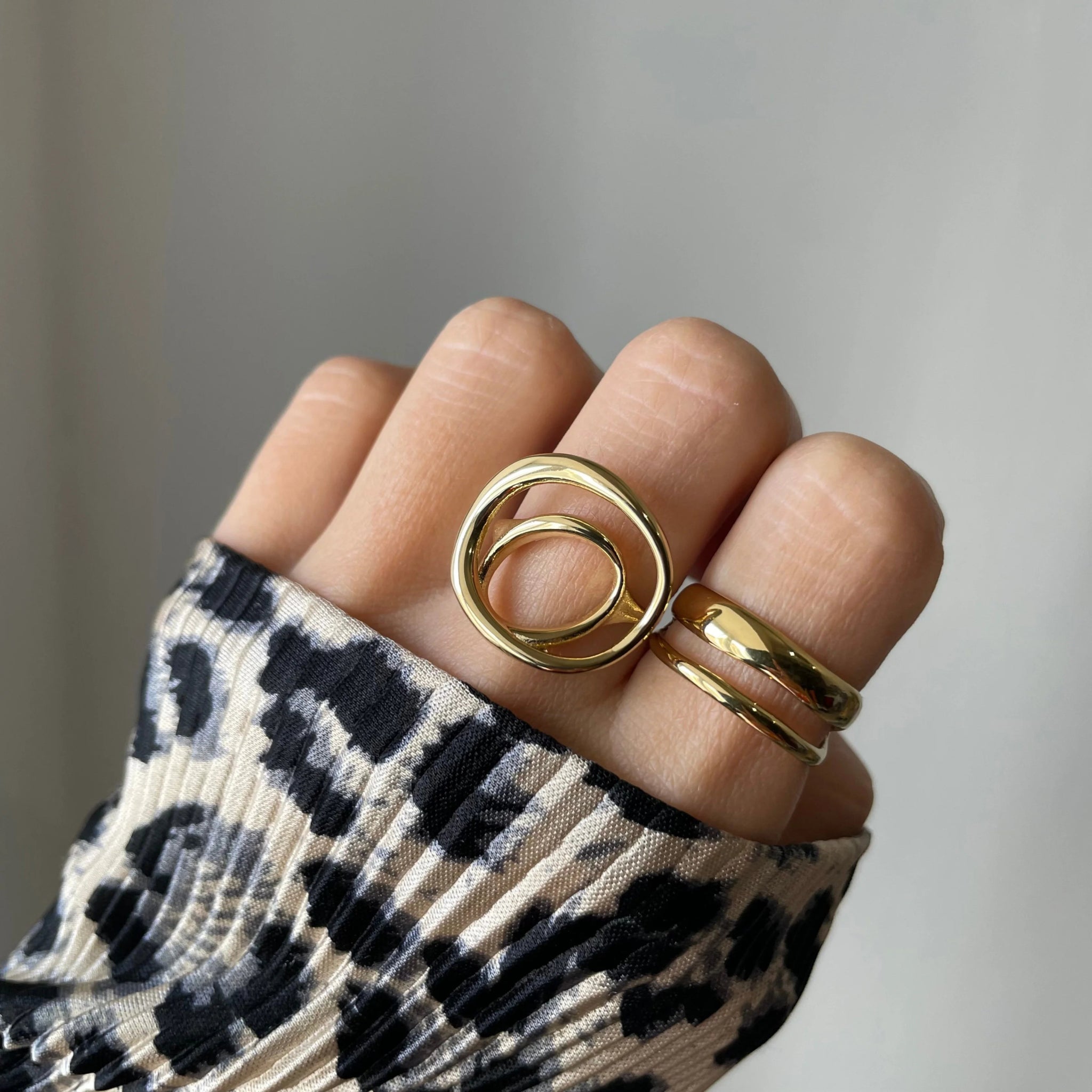 Bague double rangs Filipa portée en accumulation avec une bague cercle géométrique sur main manucurée avec pull léopard.