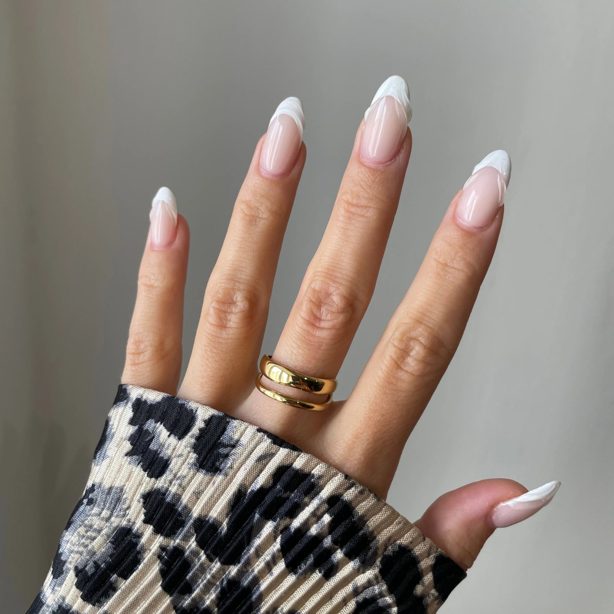 Bague double rangs Filipa portée en accumulation avec une bague cercle géométrique sur main manucurée avec pull léopard.