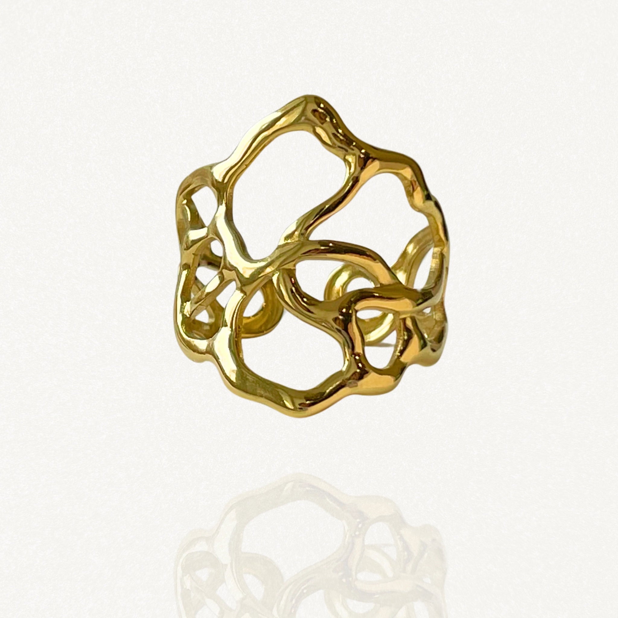 Bague large ajourée en acier inoxydable doré au design organique et irrégulier évoquant des végétaux entrelacés.