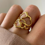 Gros plan bague Flora à structure graphique et aérée portée au doigt, style moderne et artistique.