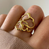 Gros plan bague Flora à structure graphique et aérée portée au doigt, style moderne et artistique.