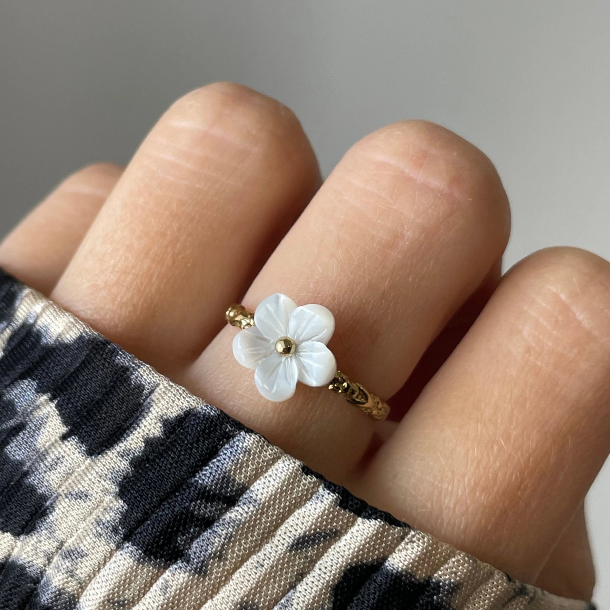 Bague Florina motif fleur portée sur une main manucurée avec pull léopard, style tendance.