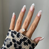 Bague Florina motif fleur portée sur une main manucurée avec pull léopard, style tendance.