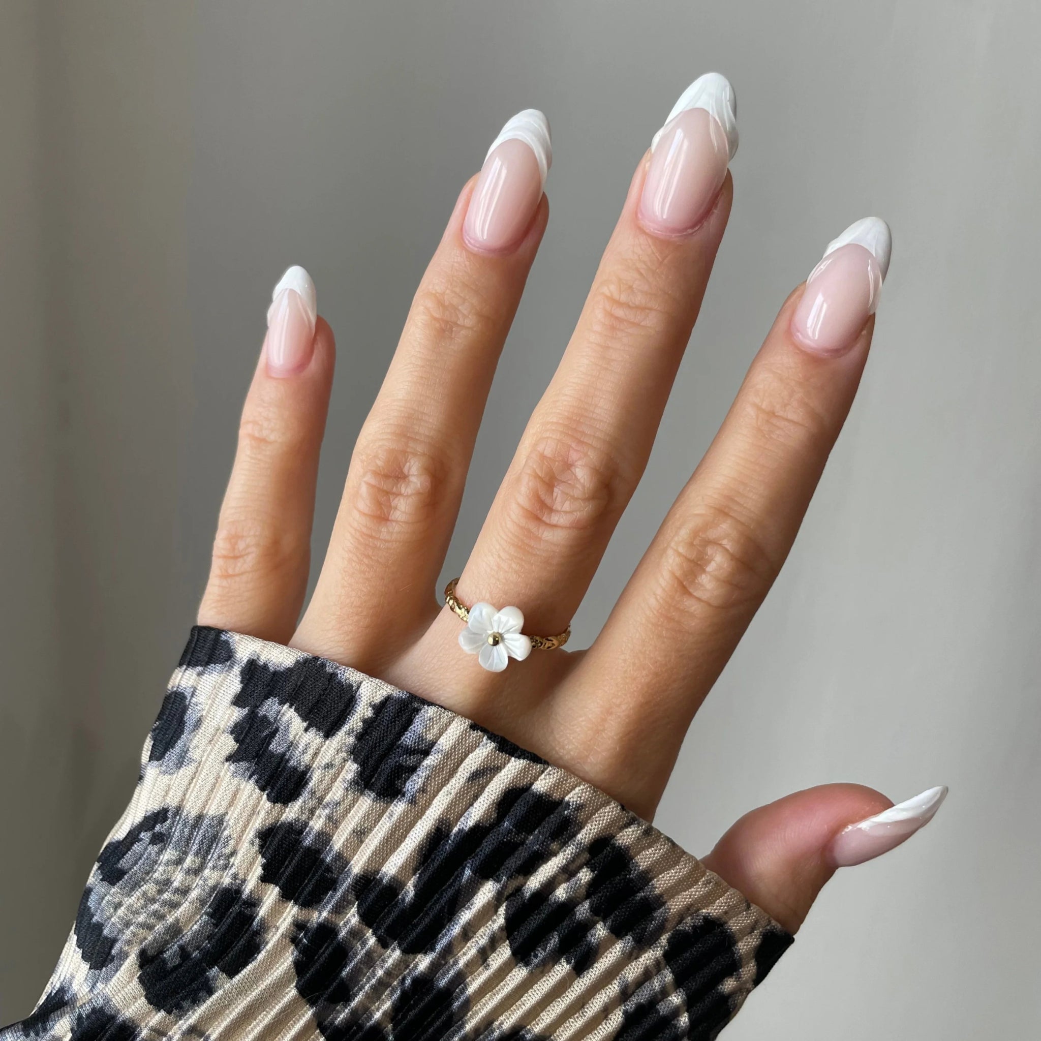Bague Florina motif fleur portée sur une main manucurée avec pull léopard, style tendance.