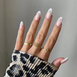 Bague étoile Gloria portée en accumulation (stacking) avec une bague bandeau texturée sur une main.