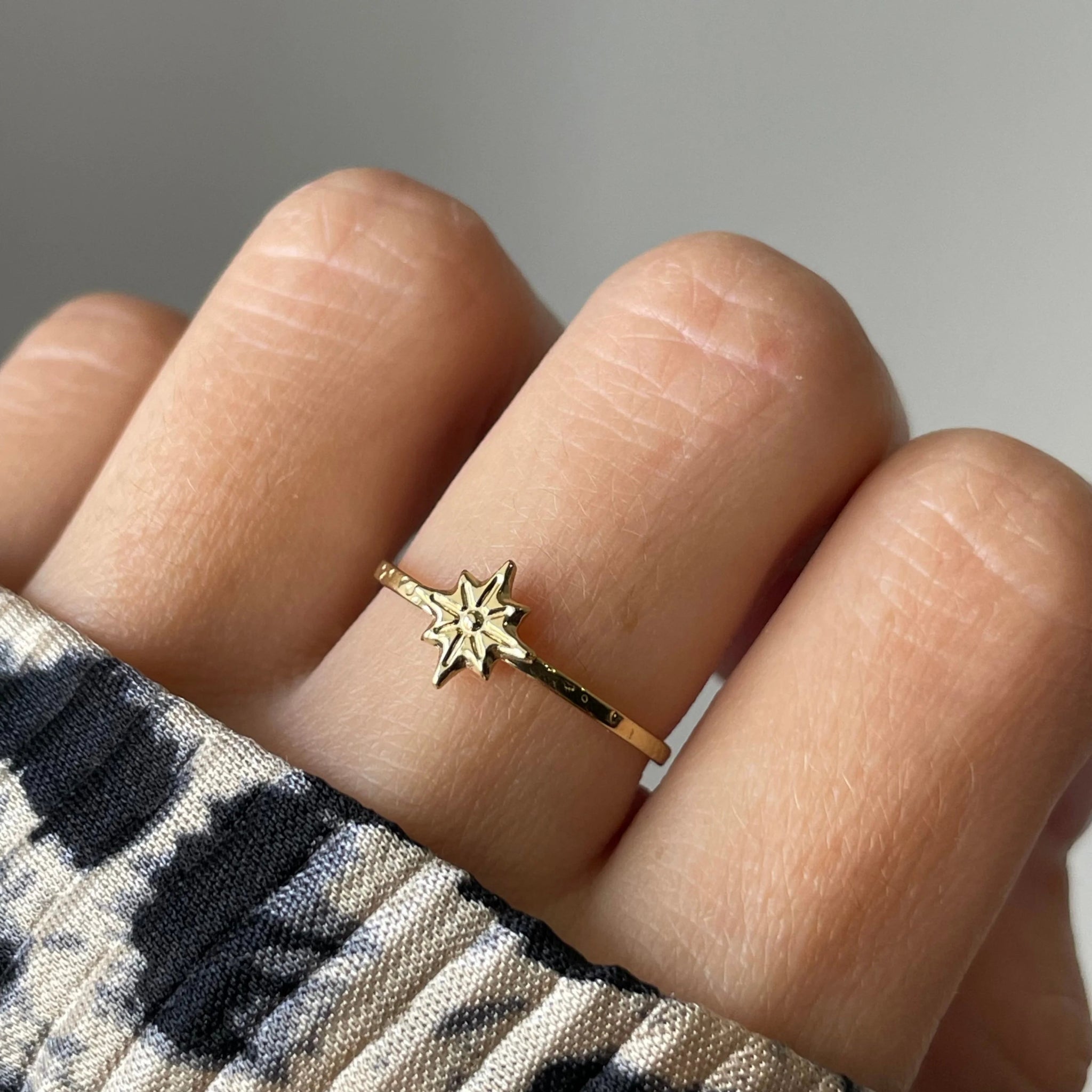 Gros plan bague fine Gloria motif étoile polaire portée au doigt, style minimaliste et céleste.