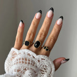 Bague Inès portée en accumulation (stacking) avec d'autres bagues dorées serties de pierres noires pour un look Black & Gold.