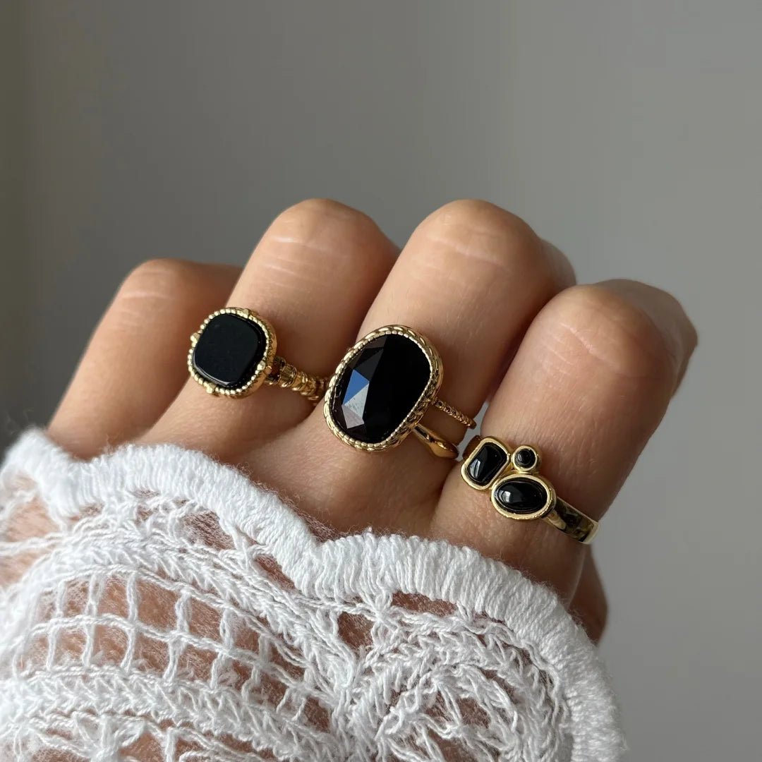 Bague Inès portée en accumulation (stacking) avec d'autres bagues dorées serties de pierres noires pour un look Black & Gold.
