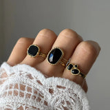 Bague Inès portée en accumulation (stacking) avec d'autres bagues dorées serties de pierres noires pour un look Black & Gold.
