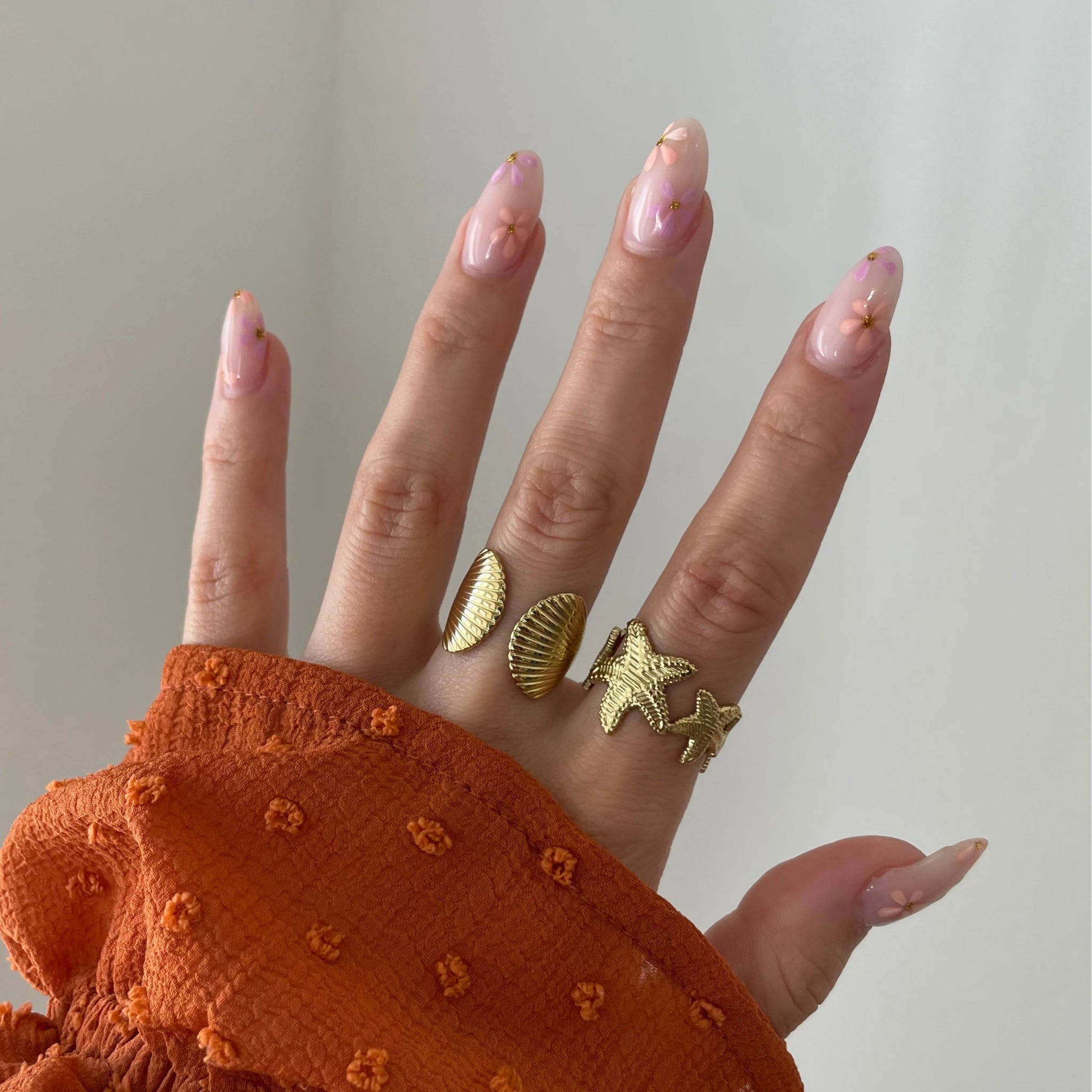 Bague coquillage Jana portée en accumulation (stacking) avec une bague étoile de mer pour un look sirène complet.