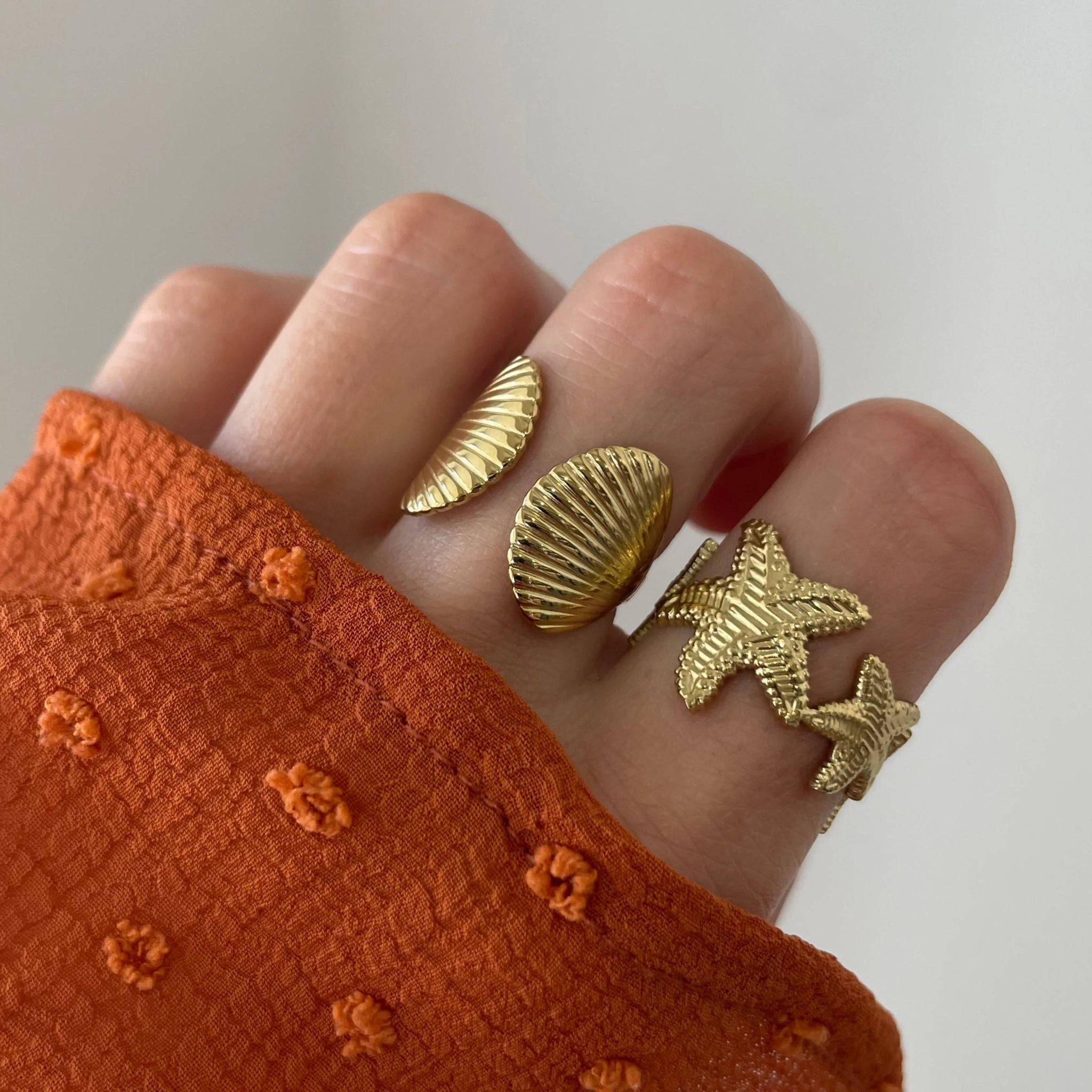 Bague coquillage Jana portée en accumulation (stacking) avec une bague étoile de mer pour un look sirène complet.