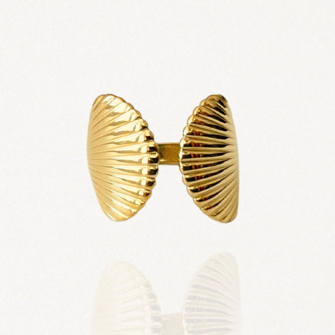 Bague ouverte ajustable en acier inoxydable doré avec motif double coquillage Saint-Jacques strié sur fond blanc.