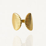 Bague ouverte ajustable en acier inoxydable doré avec motif double coquillage Saint-Jacques strié sur fond blanc.