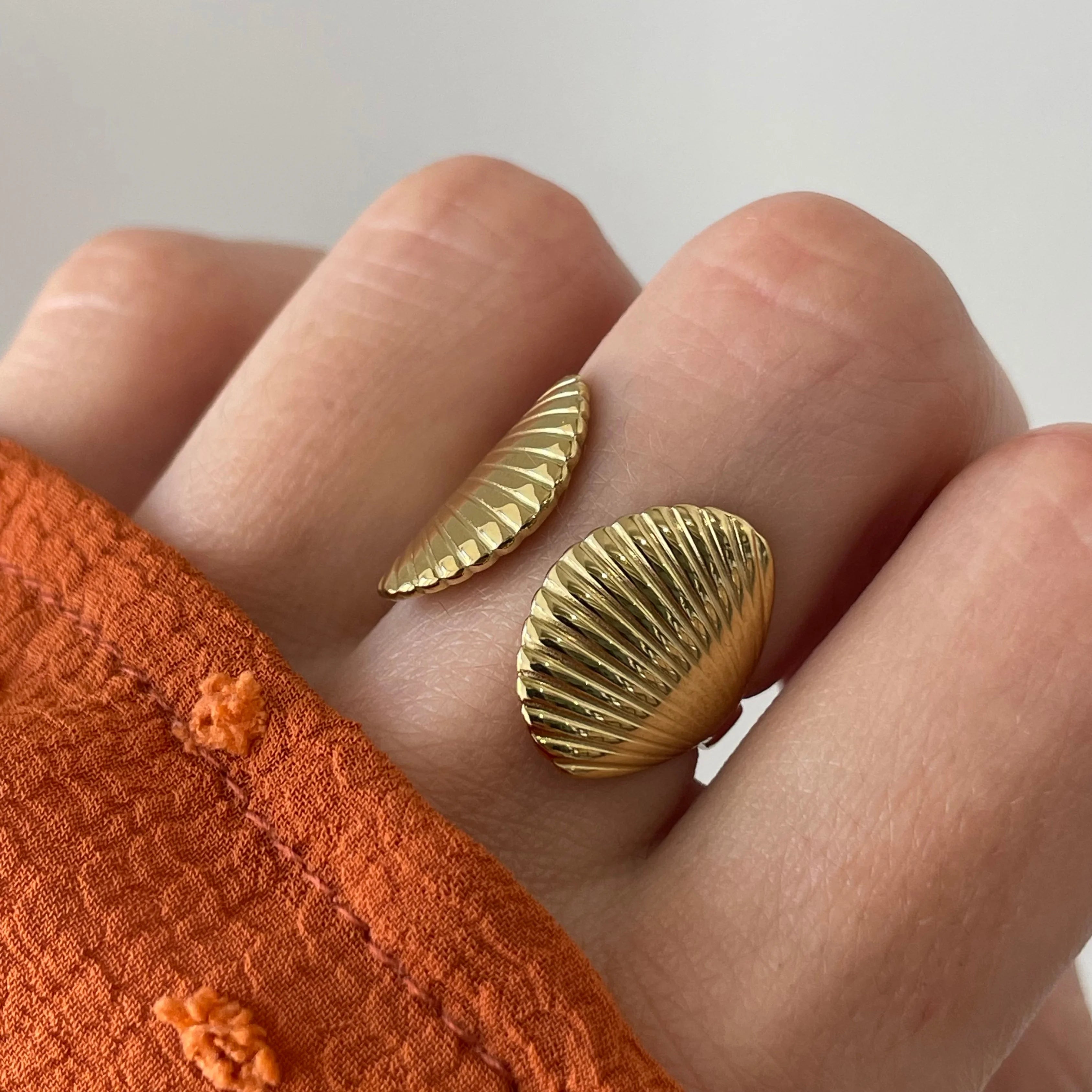 Gros plan bague Jana forme coquillages marins portée au doigt, style vacances et été.