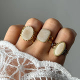 Bague Klarisa portée en accumulation (stacking) avec d'autres bagues larges style cabochon blanc.