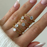 Bague fine à pierre Léonie portée en accumulation (stacking) avec d'autres bagues dorées minimalistes sur une main.