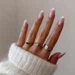 Bague fine à pierre Léonie portée en accumulation (stacking) avec d'autres bagues dorées minimalistes sur une main.