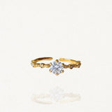 Bague fine solitaire en acier inoxydable doré avec pierre blanche scintillante type zirconium et anneau texturé sur fond blanc.