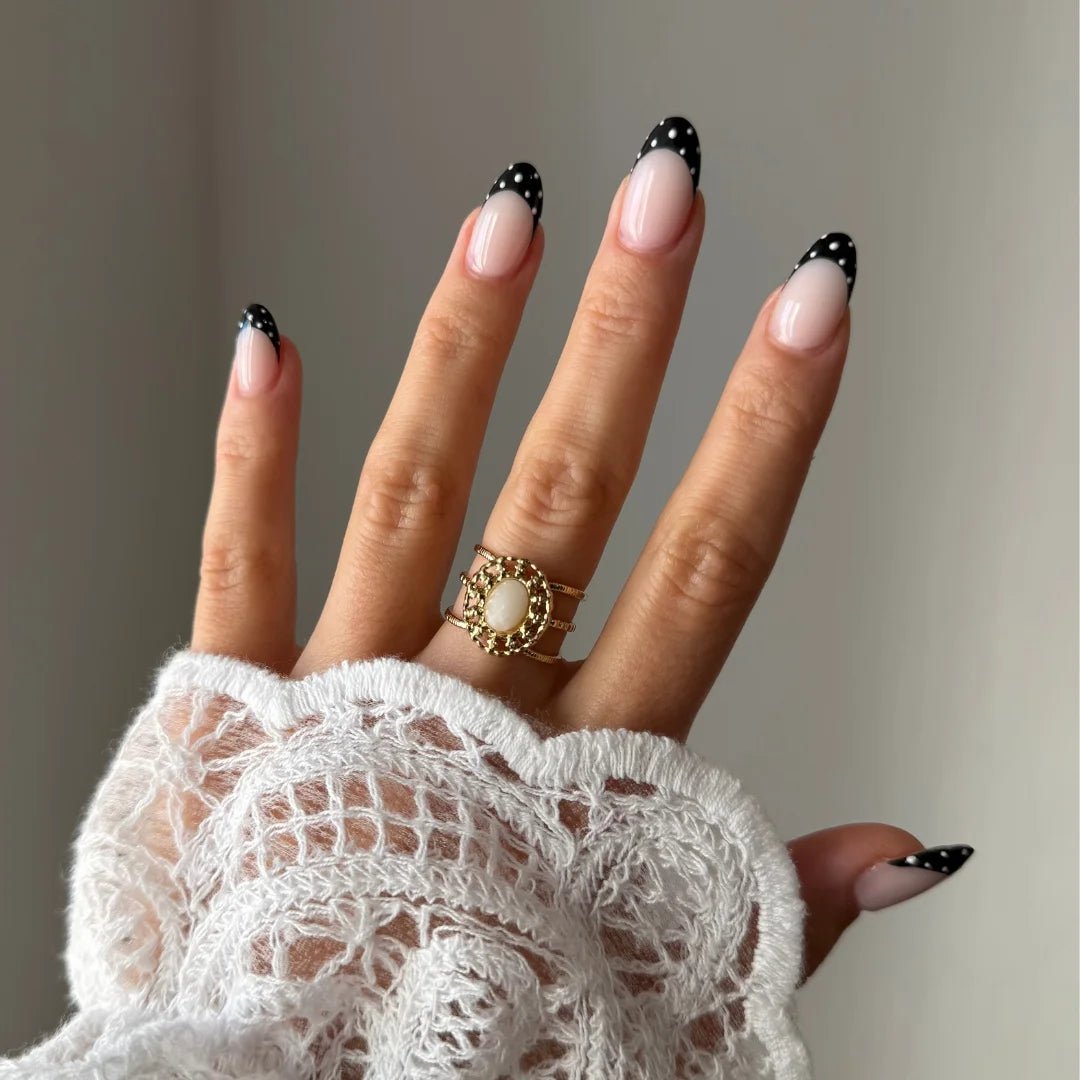 Bague Lou-Anne style vintage bohème avec pierre blanche portée sur une main avec manche en dentelle.