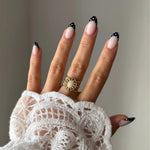 Bague Lou-Anne style vintage bohème avec pierre blanche portée sur une main avec manche en dentelle.