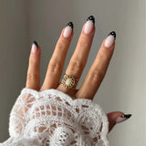 Bague Lou-Anne style vintage bohème avec pierre blanche portée sur une main avec manche en dentelle.